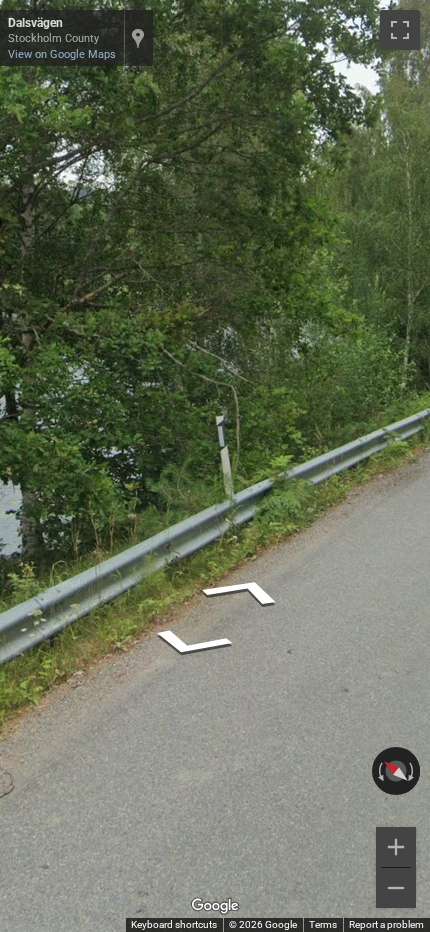 Swedish flat white bollard with a diagonal black stripe and a grey reflector on its flat top.