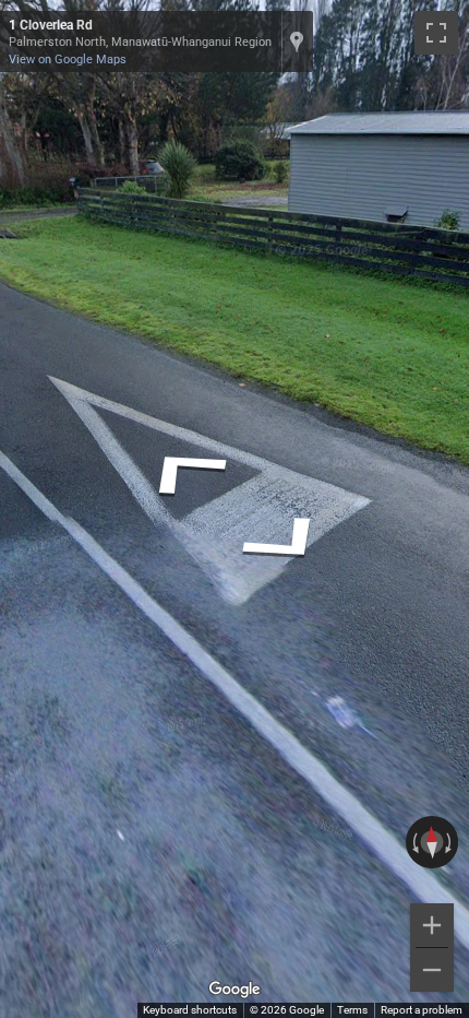 New Zealand road marking: A white triangle painted on the asphalt at an intersection, indicating 'give way'.