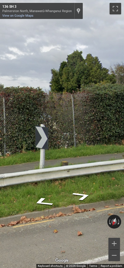 New Zealand chevron road sign with a black background and white arrows pointing towards a sharp curve.
