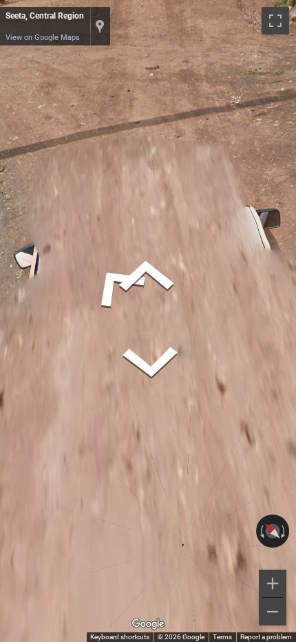 Ugandan Street View car, white, with prominent square side mirrors, driving on a paved road.
