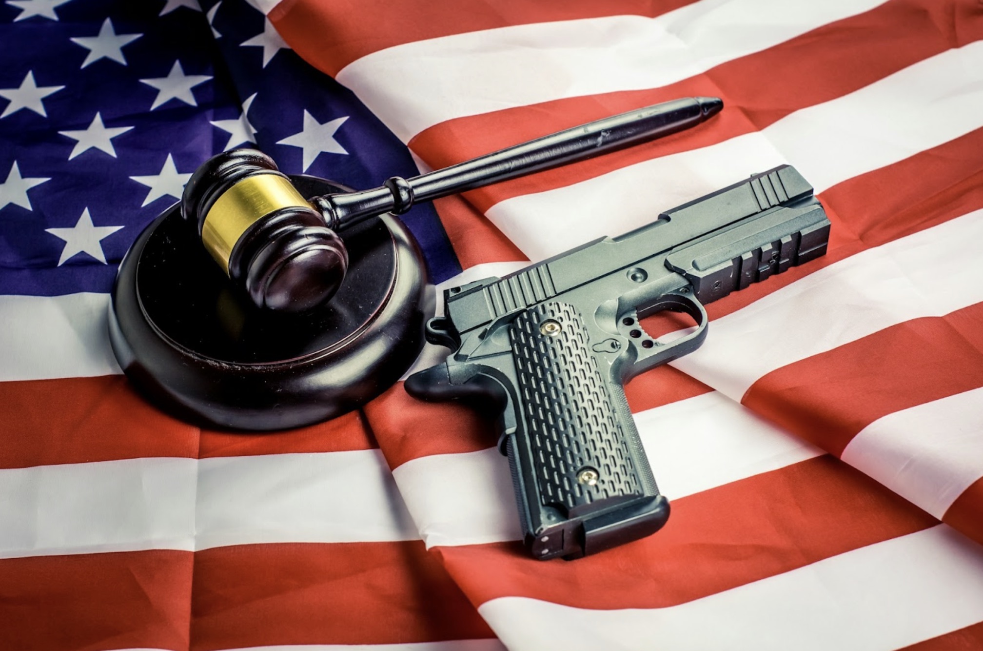 Wooden judge gavel and black colored gun over USA flag