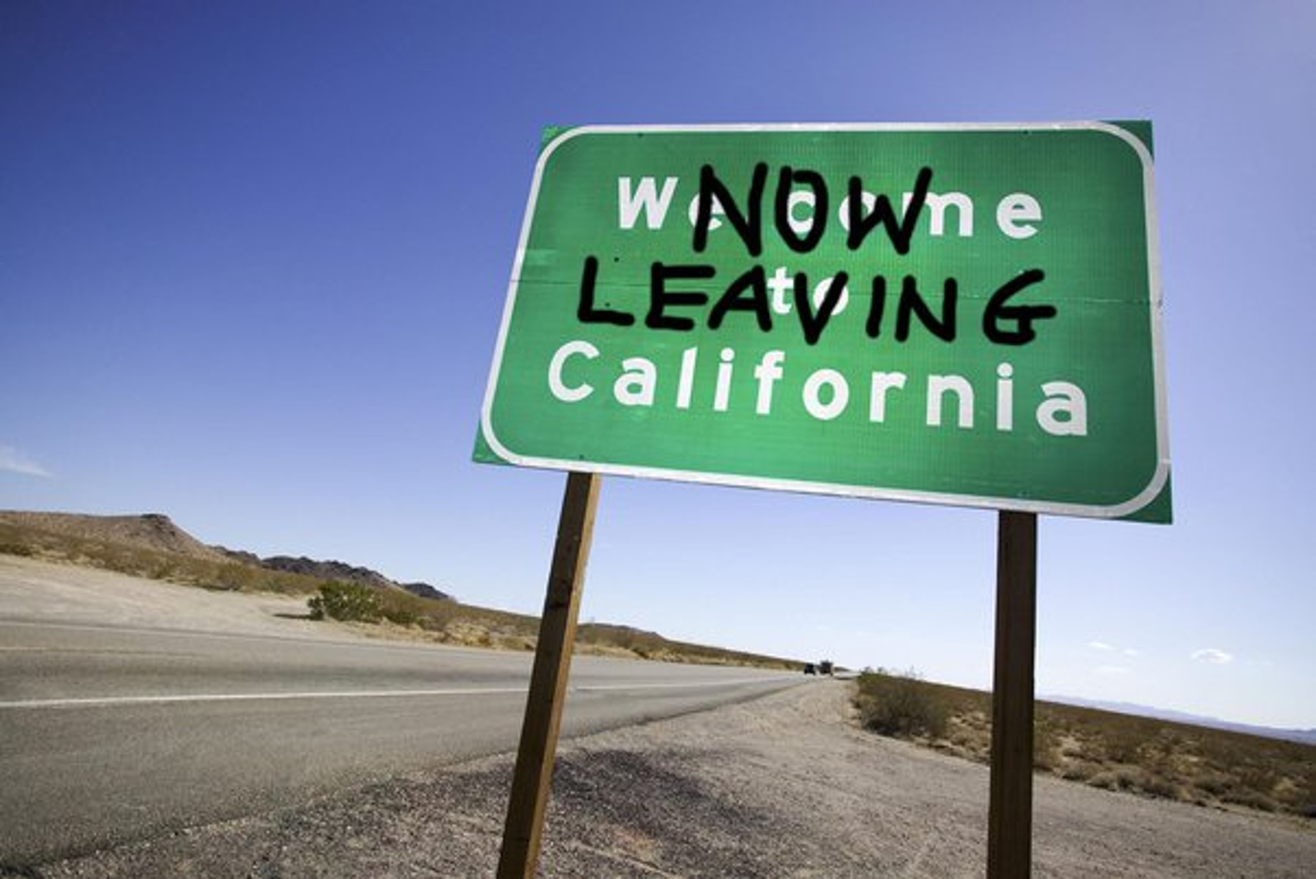 A green road sign on the side of a highway that reads "Welcome to California" with "Now Leaving" spray painted in black