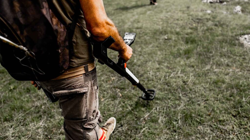 Person with metal detector on grass