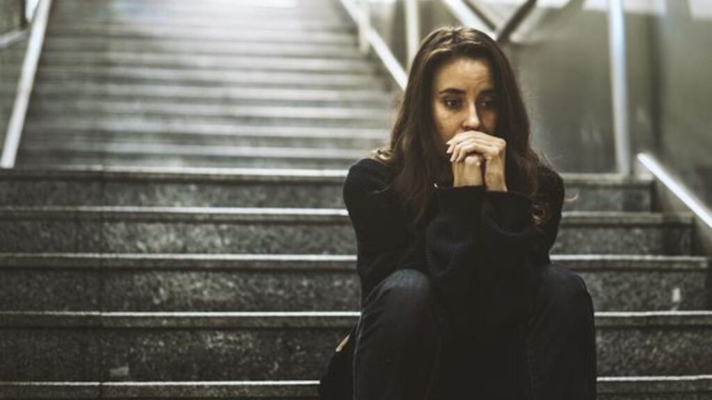 Woman sitting on the stairs thinking intently.