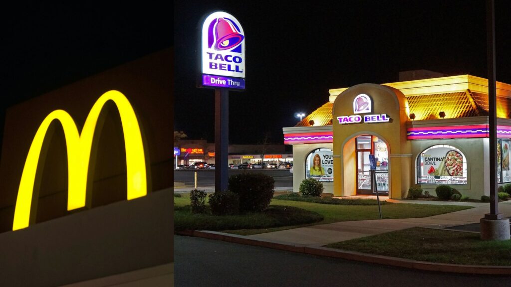 he glowing golden arches of a McDonald's sign at night on the left, with the brightly lit purple and blue Taco Bell Drive-Thru sign in the background on the right