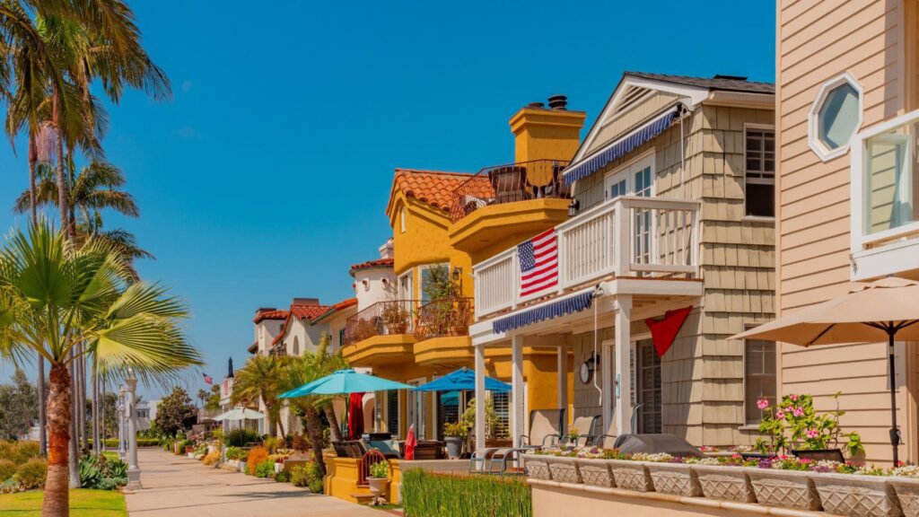 A row of colorful houses sit next to a boardwalk on a nice day