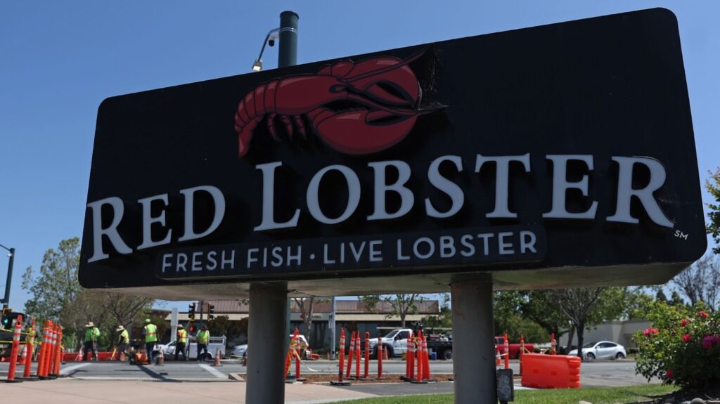 A sign for a Red Lobster restaurant. The sign has an image of a red lobster, and underneath says “Fresh Fish. Live Lobster.”