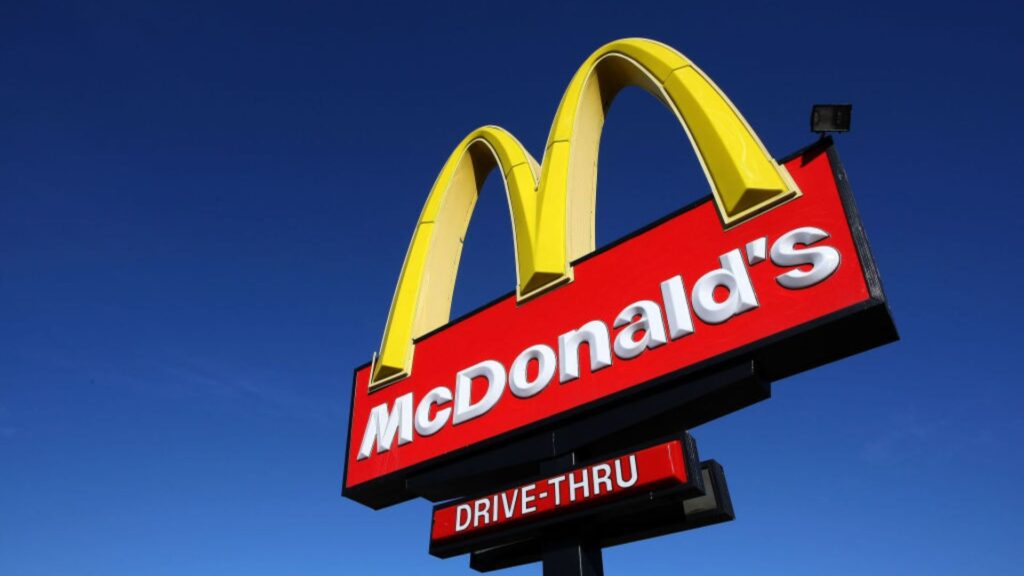 A McDonald's sign with a blue sky background. The text on the sign reads "McDonald's" and "Drive-Thru".