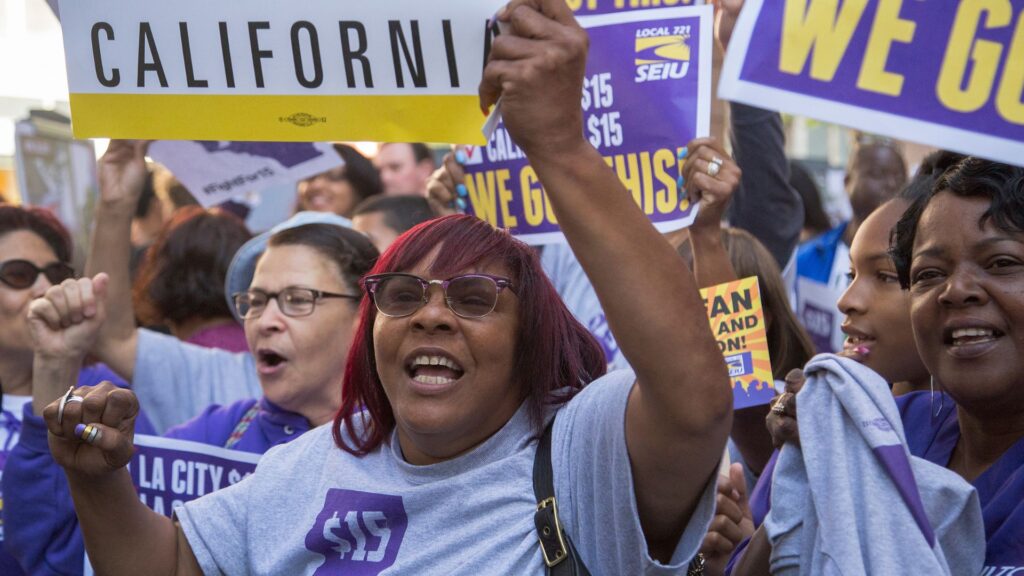 Workers protesting and holding up signs demanding for a higher minimum wage.