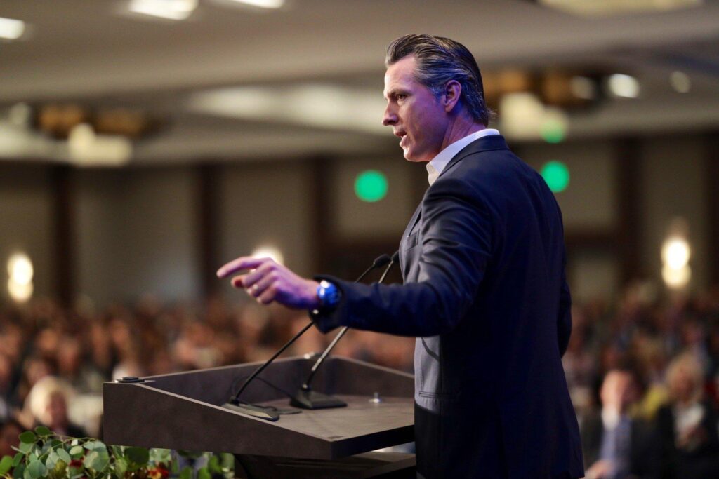 A man standing on a podium speaking in front of a crowd of audience