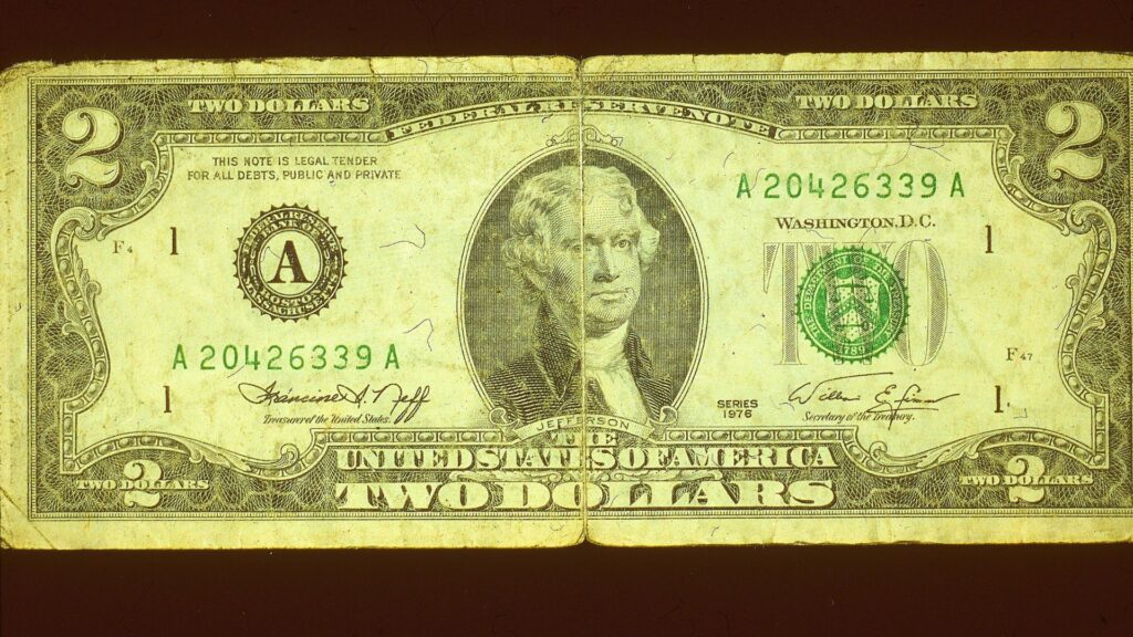 An old, slightly torn, $2 note.