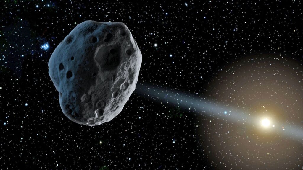 A realistic depiction of a large asteroid with a rough, cratered surface, floating in space against a backdrop of stars and a distant sun