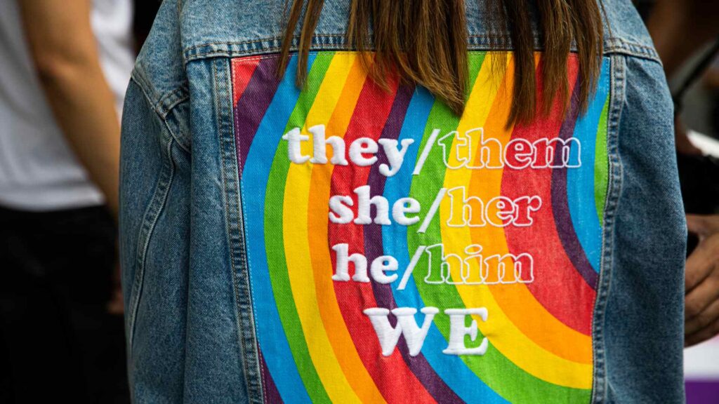 A jacket with rainbow colors showing off different pronouns.