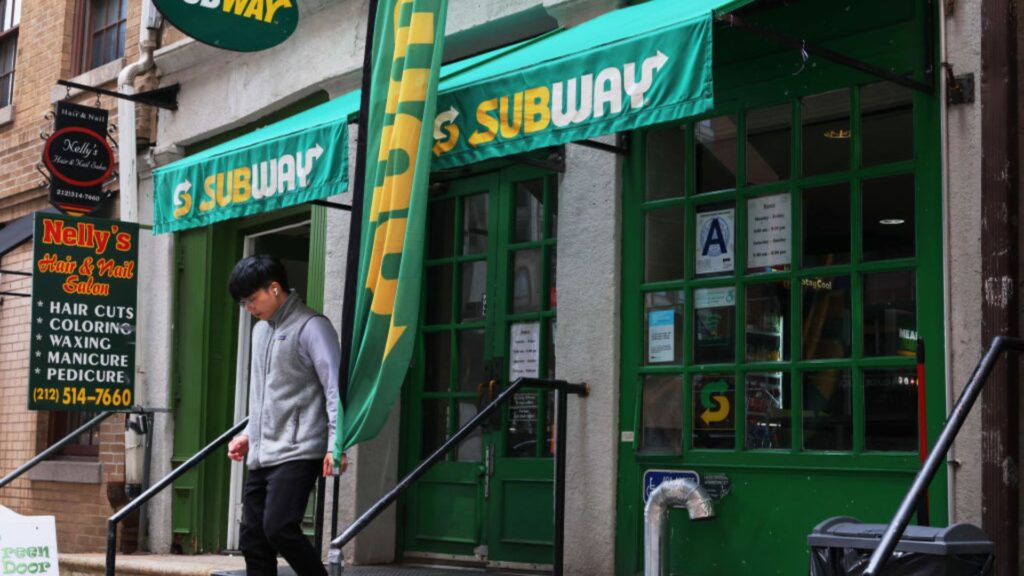 A man walking out of a Subway.