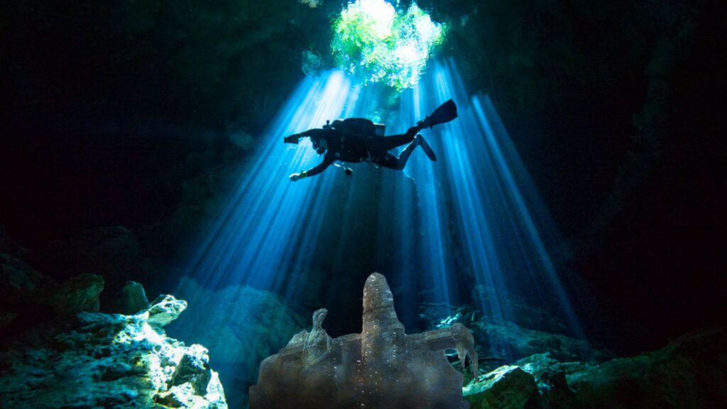 Scuba diver in an underwater cave, there is a bust and architecture imposed on top