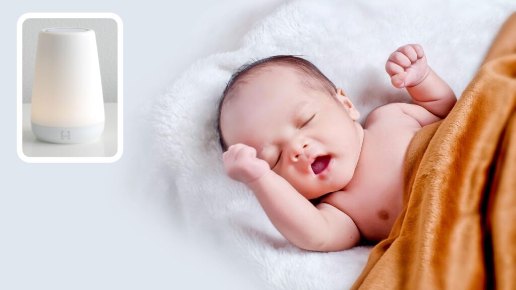 A close-up of a Hatch sound machine; a baby yawing underneath a blanket.