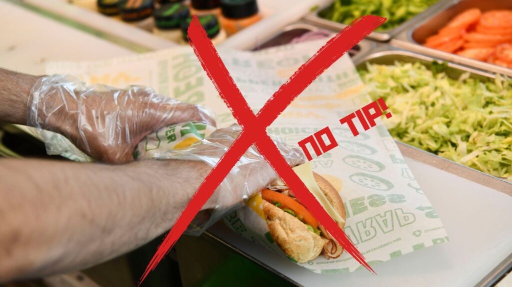 A person’s hands in clear gloves wrapping a Subway sandwich in a paper wrapper. Over the image is a large red X with the words “no tip” next to it.