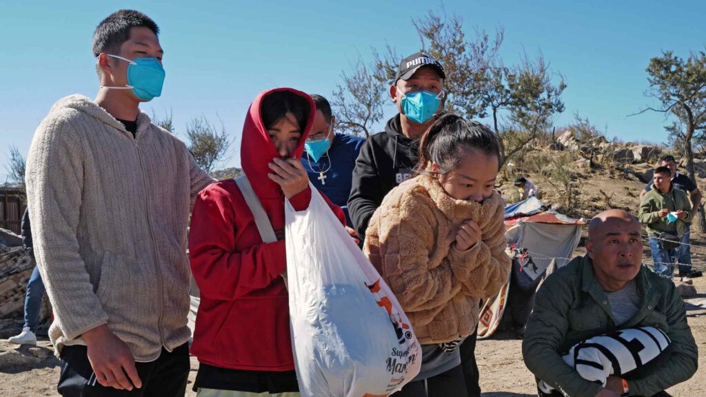 Chinese migrants huddle for warmth near the US southern border.