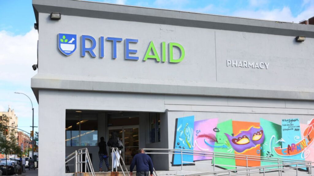 A Rite Aid store in an urban setting featuring a colorful mural with whimsical designs and the word 'Carnival' painted on its side