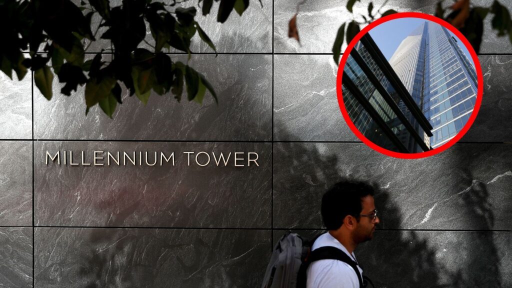 A man walking past the Millennium Tower sign and a picture of the tower is in the corner.