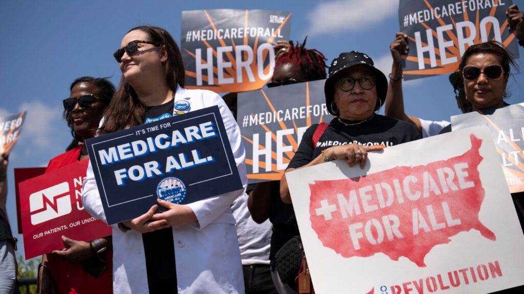 People as part of a public demonstration holding “Medicare For All” signs.