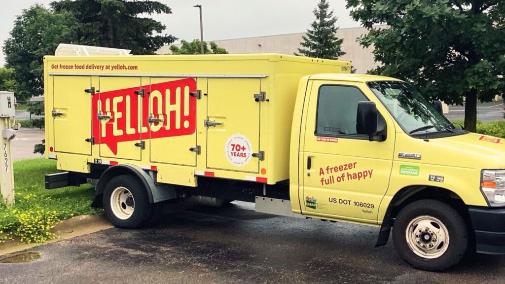 A bright yellow delivery truck labeled "YELLOH!" parked on a street, advertising "Get frozen food delivery at yelloh.com" and promoting "A freezer full of happy"