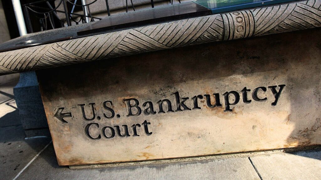 A stone sign outside a U.S. Bankruptcy Court building, pointing to the entrance with a carved arrow