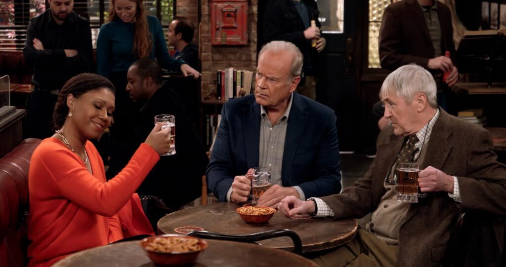 Kelsey Grammer as Frasier Crane sitting in a bar with Toks Olagundoye as Professor Olivia Finch and Nicholas Lyndhurst as Professor Alan Cornwall in "Frasier"