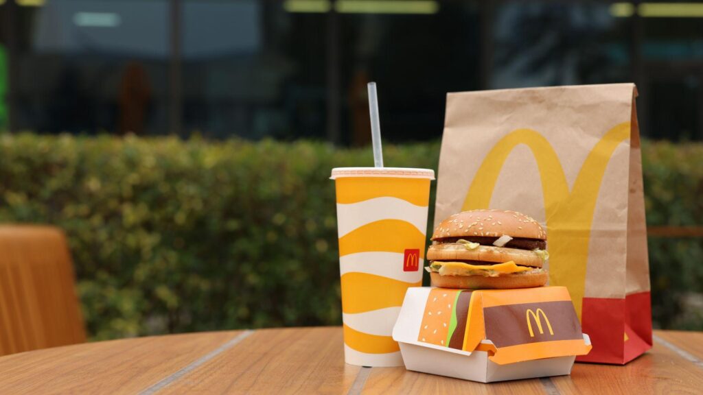 A McDonalds burger, box, bag, and drink are on a table