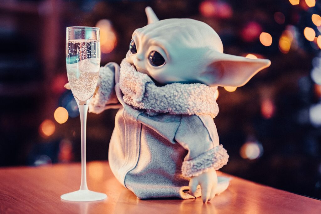 Baby Yoda holding an oversized glass of champagne