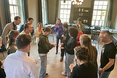 terwijl de collega's supporteren, spelen twee deelnemers het spelletje 'blad-steen-schaar'