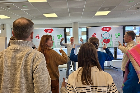 De deelnemers van de interactieve presentatie steken hun duimen in de lucht, waardoor ze zich vanzelf vrolijk voelen.