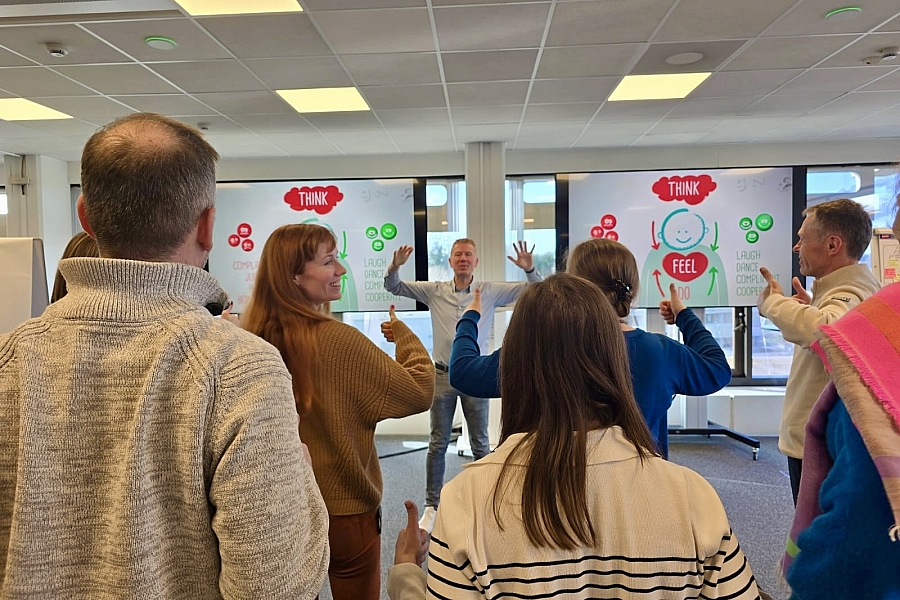 De deelnemers van de interactieve presentatie steken hun duimen in de lucht, waardoor ze zich vanzelf vrolijk voelen.