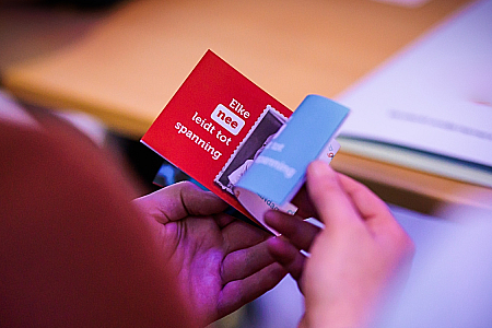 Een deelnemer houdt een samenvatting in de hand van de interactieve presentatie over duurzaam geluk - Elke NEE leidt tot spanning, elke JA leidt tot ontspanning.