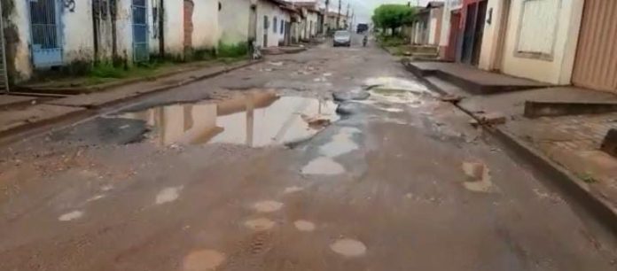 Motociclista mostra dificuldade em passar em rua que está com buracos há meses