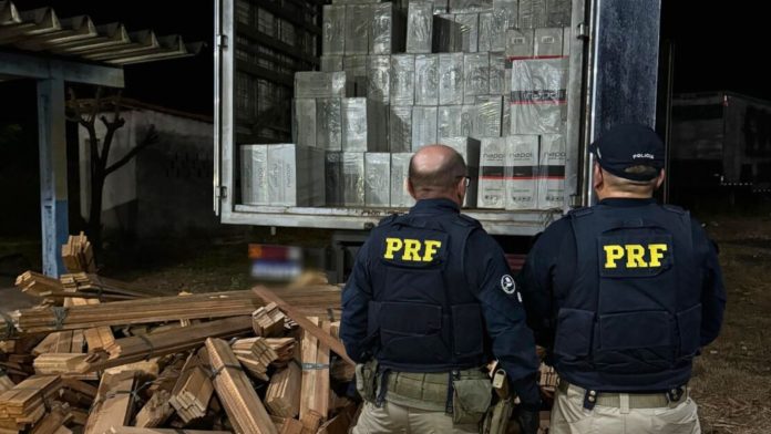 PRF apreende mais de 272 mil maços de cigarros contrabandeados na BR-135 no MA Durante a fiscalização, o motorista do caminhão, um homem de 41 anos, mostrou-se bastante inquieto, tentando se afastar do veículo e apresentando versões desconexas sobre a viagem que realizava. Questionado sobre a carga, ele afirmou transportar madeira serrada, mas não possuía nenhuma documentação do produto florestal. Ao inspecionar o compartimento de carga, os policiais identificaram um volume diferente no fundo das peças de madeira. Foi então que descobriram que a madeira serrada estava sendo usada para esconder a grande quantidade de cigarros contrabandeados. Foram localizadas 544 caixas grandes, de marcas variadas e de origem estrangeira, totalizando 272.200 maços de cigarros. O condutor alegou não saber o que transportava e disse apenas desconfiar de algo estranho, pois teria recebido o caminhão lacrado no estado do Pará para fazer a entrega em uma cidade que seria informada durante o percurso pela pessoa que o contratara. O motorista foi detido por contrabando e, junto com o caminhão e a carga apreendida, encaminhado ao plantão da Polícia Civil em Codó (MA) para os procedimentos legais cabíveis e continuidade das investigações.