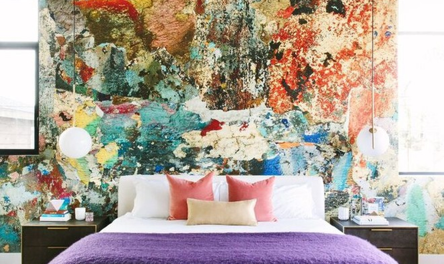 Mural accent wall with abstract landscape shapes behind a curved sofa and low sculptural coffee table