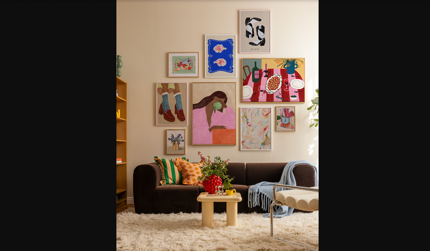 Curated gallery wall with mixed frames, folk art, and a warm neutral sofa below
