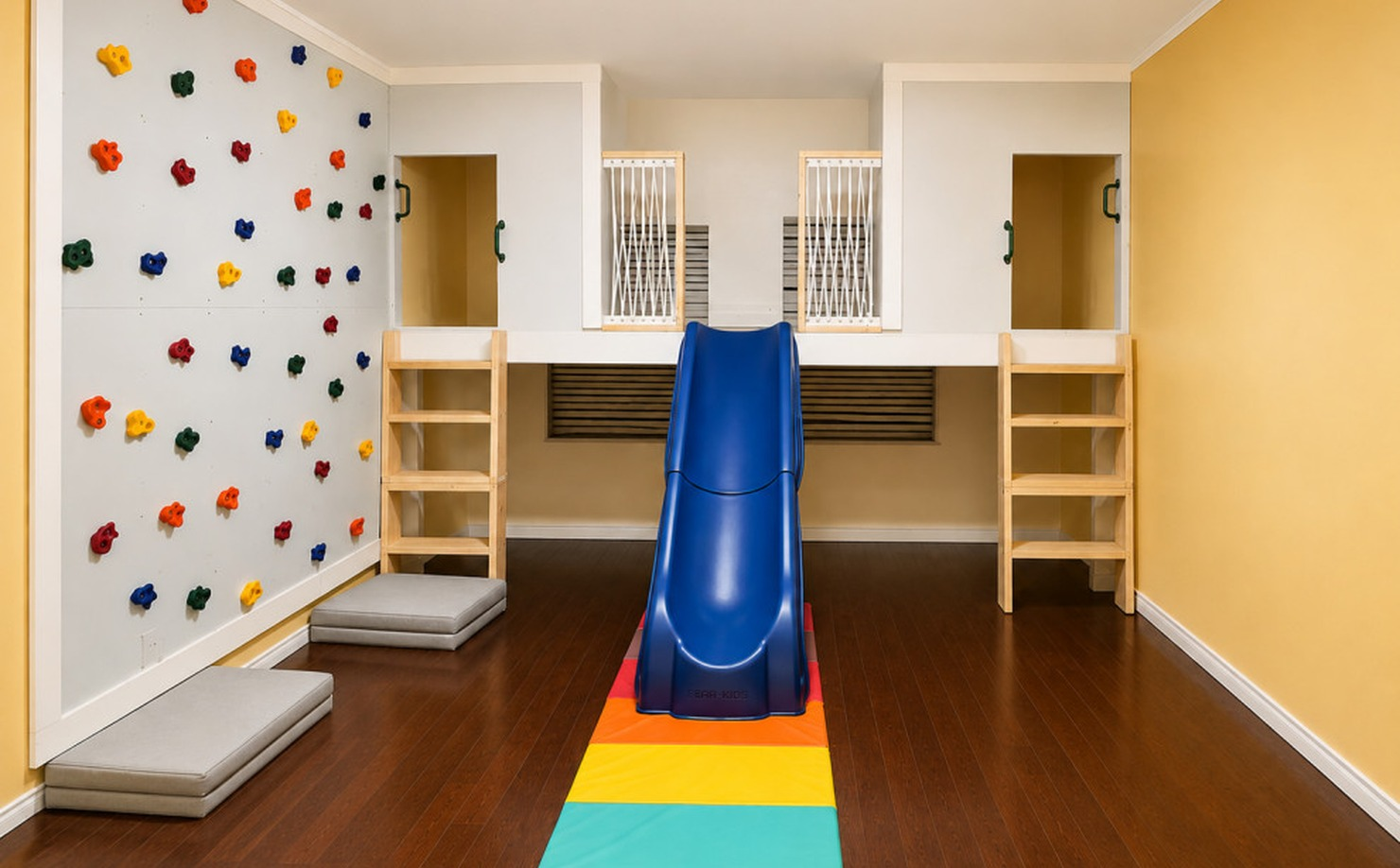 Kids’ game room with a climbing wall, slide, raised play loft, and built-in storage