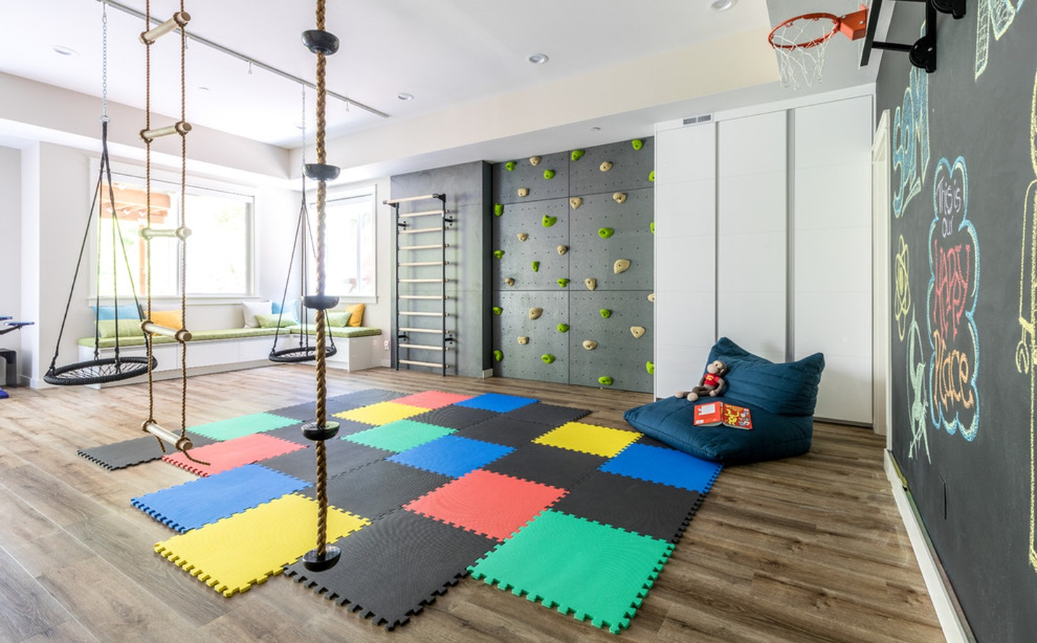 Basement kids’ game room with basketball hoop, ropes, climbing bars, swing chairs, and built-in storage