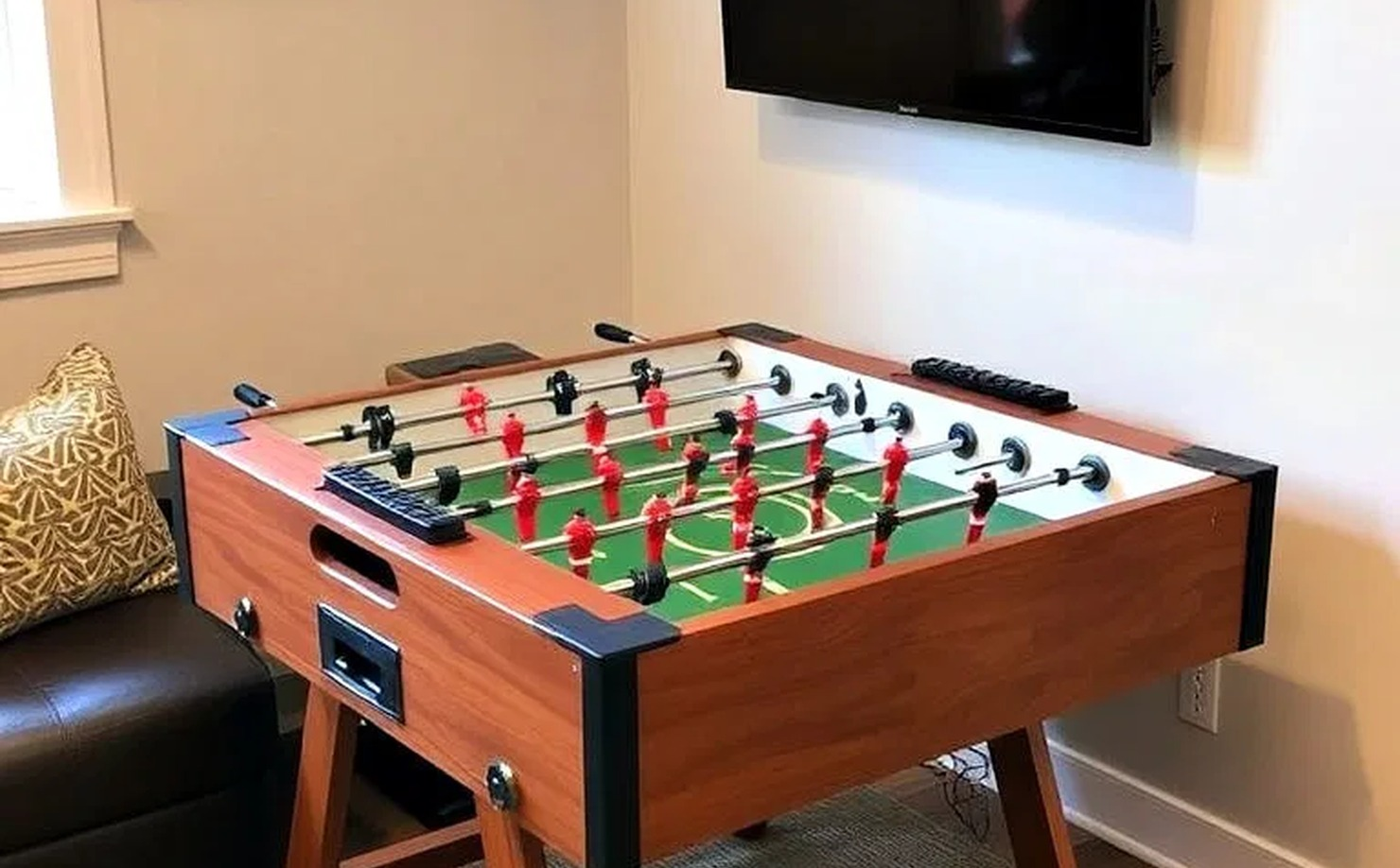 Small game room corner with vintage foosball table, midcentury lounge chairs, concrete floor, and white walls