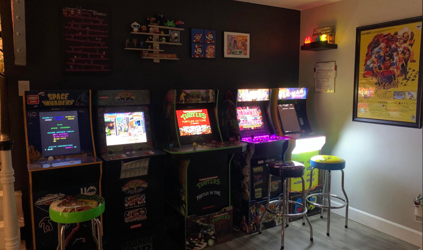 Budget retro arcade corner with neon sign, arcade cabinet, framed posters, and stools