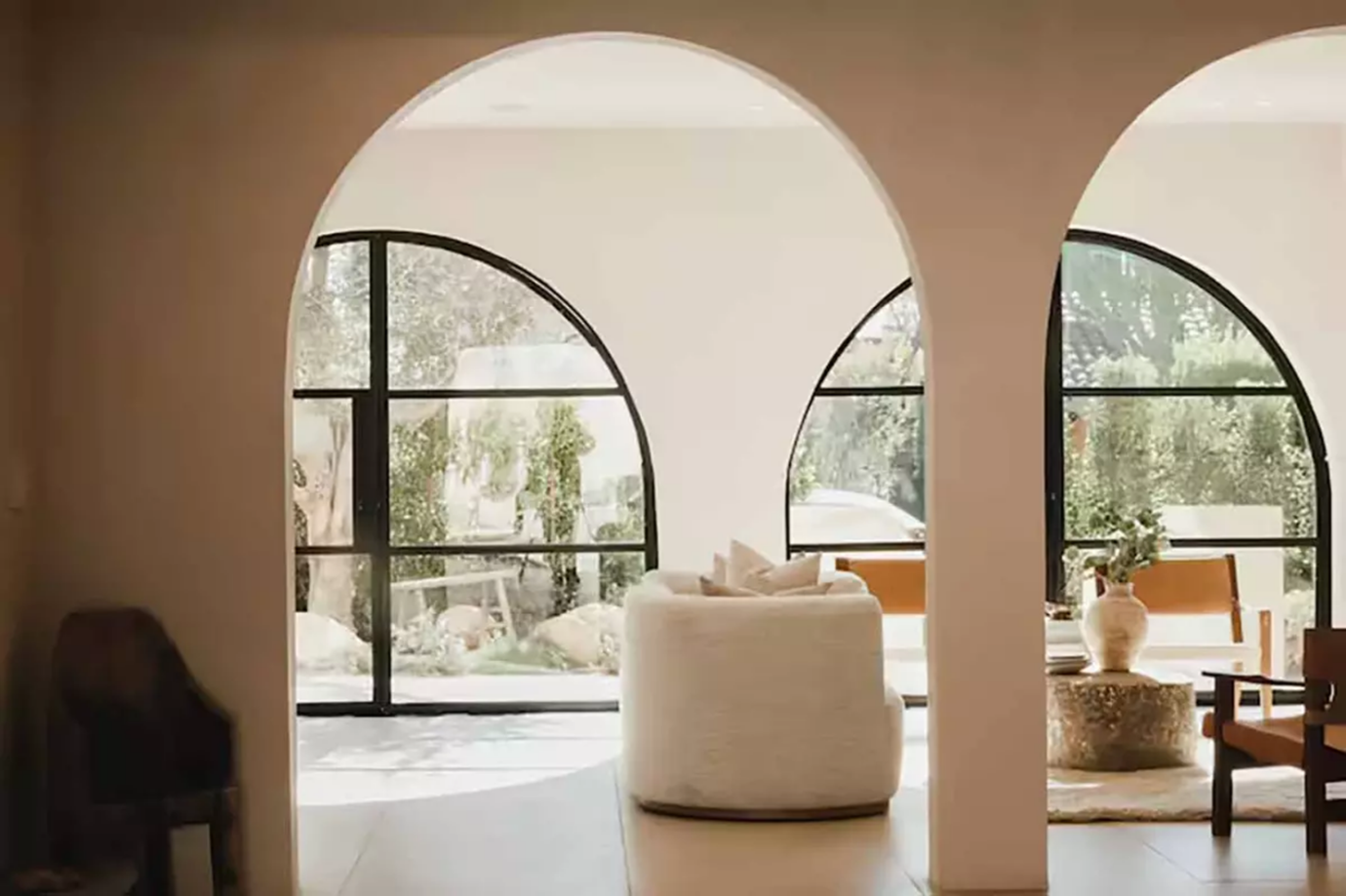 Bright living room with arched doorways, curved windows, and a rounded armchair