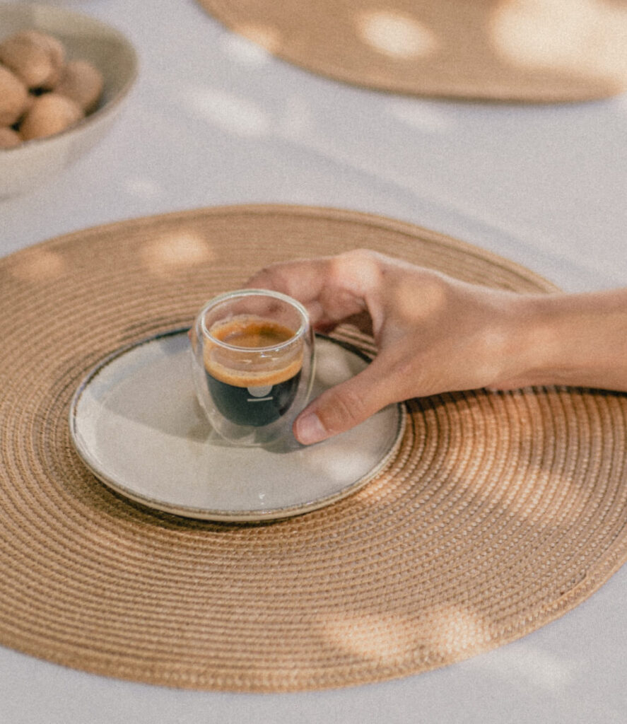 mano cogiendo vaso térmico de café de doble pared con café solo sobre plato