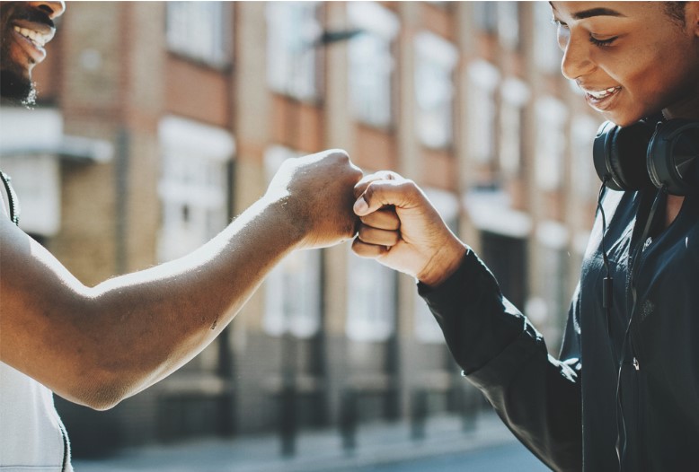 Two friends bumping fists smiling with headphones