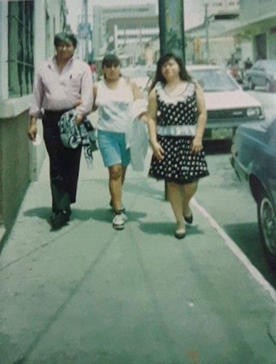 Two girls walking with their father on the sidewalk