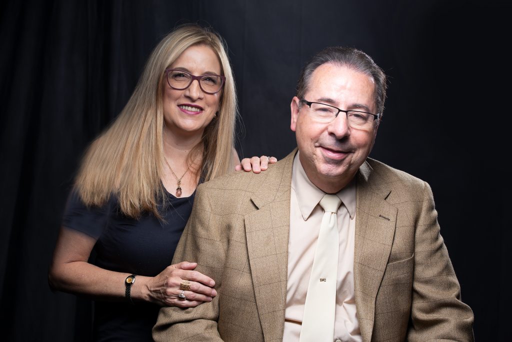 A smiling couple against a black background