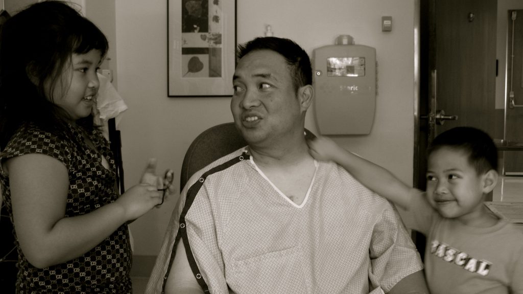 two kids with their dad in a hospital gown