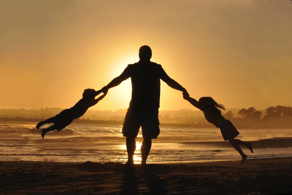 Silhouette of dad swinging his kids
