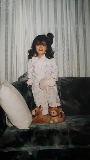 Young Mariela in her pajamas standing on a couch